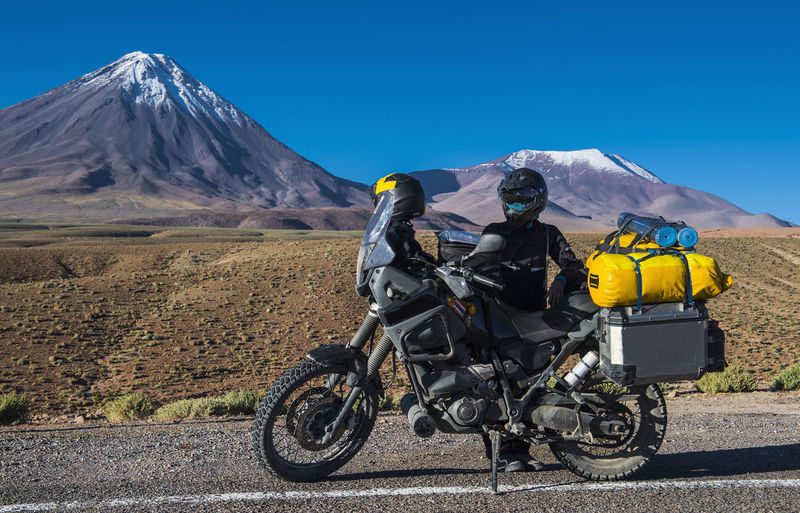 Woman behind adv motorbike, in front of the stratovolcano licancabur