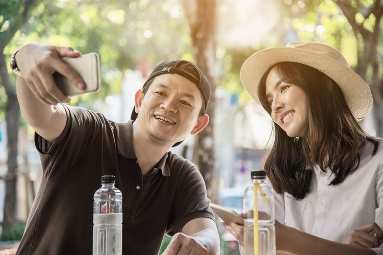 Smiling man taking selfie with girlfriend on smart phone at table