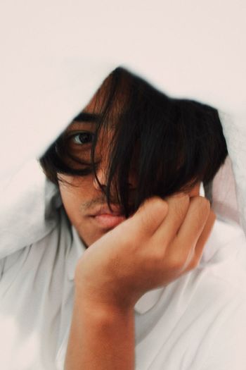 Portrait of teenage boy covering face with hair