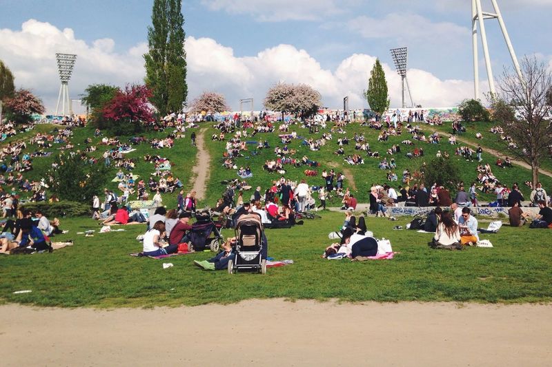 People relaxing at mauerpark against sky