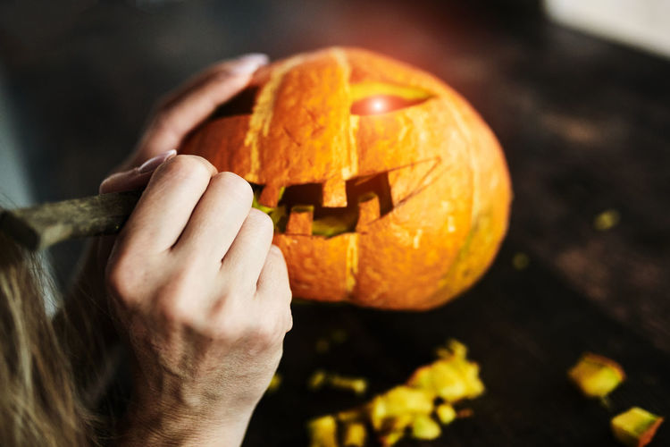 Close-up of hand holding pumpkin against blurred background