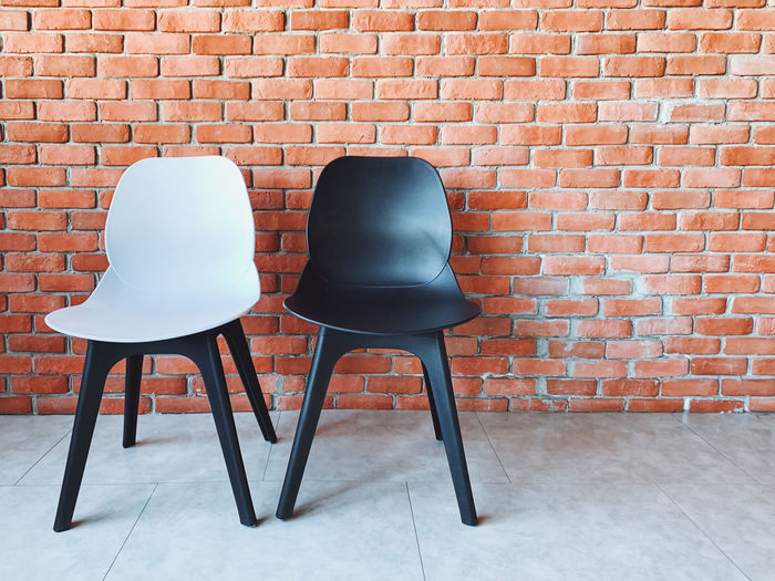 Empty chair and table against brick wall