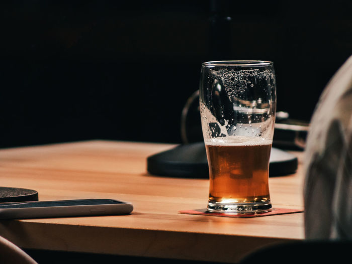 Wood table with a cristal cup and half of beer inside from a podcast studio