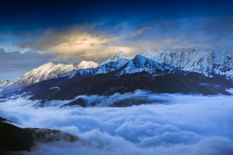 Scenic view of snowcapped mountains against cloudy sky