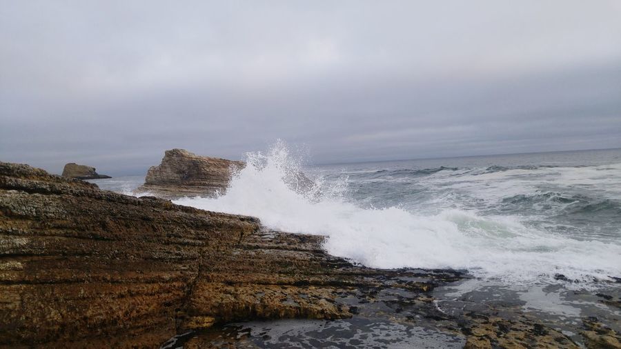 Scenic view of ocean splashing on rocks