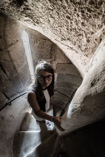 High angle portrait of girl on staircase of old building against wall