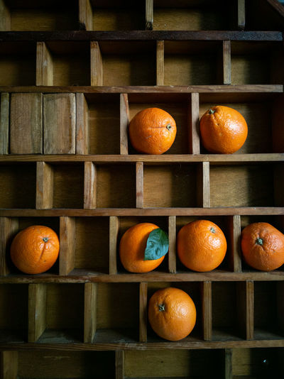 Oranges on a wooden shelf.  the background