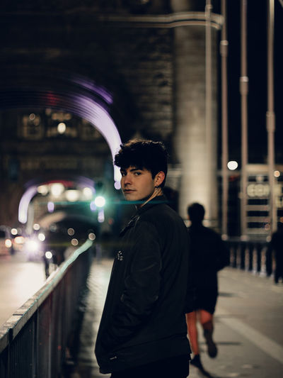 Portrait of young man standing on street at night