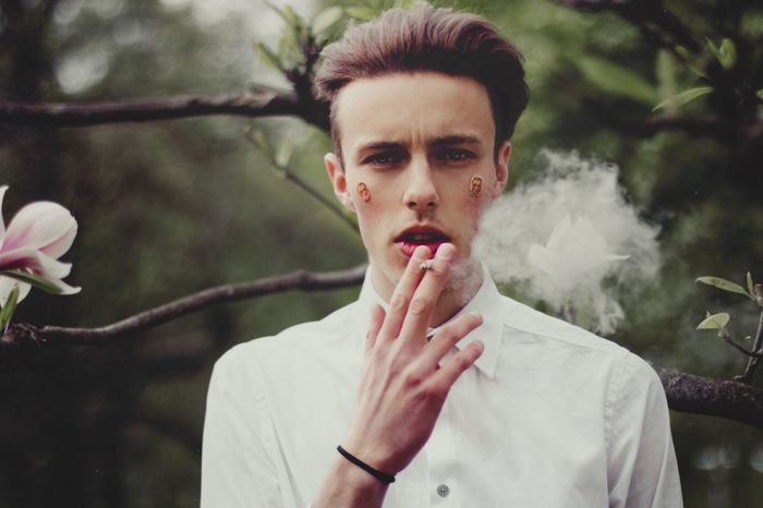 Portrait of a serious young man smoking outdoors