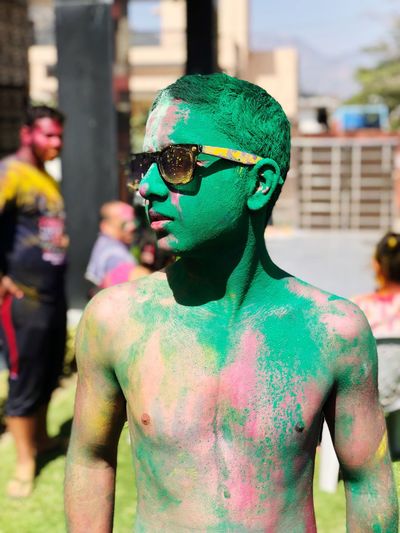 Shirtless teenage boy with green powder paint during holi celebration