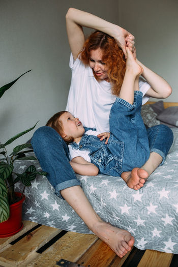 Young mother and child have fun and fool around at home on the bed