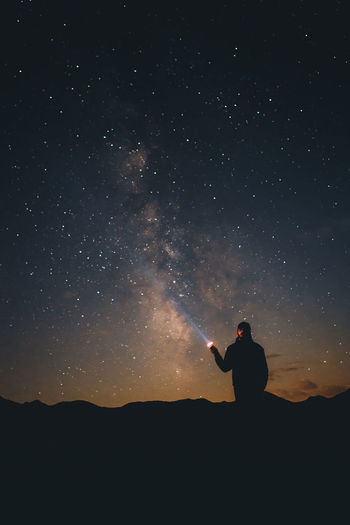 Silhouette of man standing against star field at night