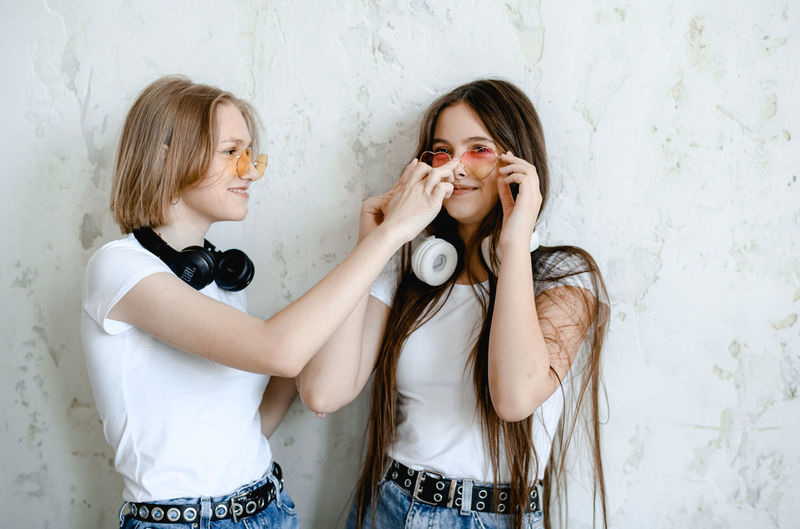Portrait of smiling young woman looking away while standing against wall