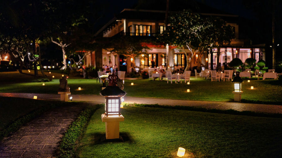 Illuminated park on footpath by building at night
