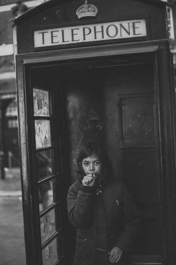 Portrait of girl standing in telephone booth