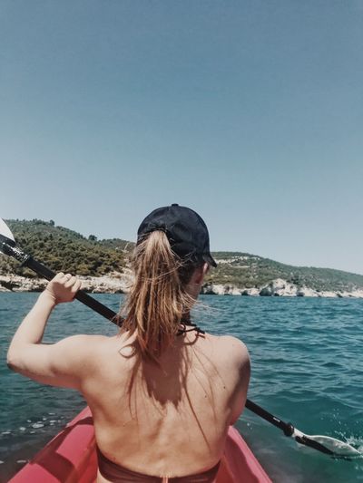 Rear view of woman canoeing on sea