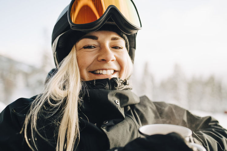 Portrait of smiling blond woman wearing ski goggles and helmet