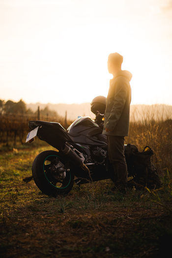 Man standing next to his powerful motorbike during sunset