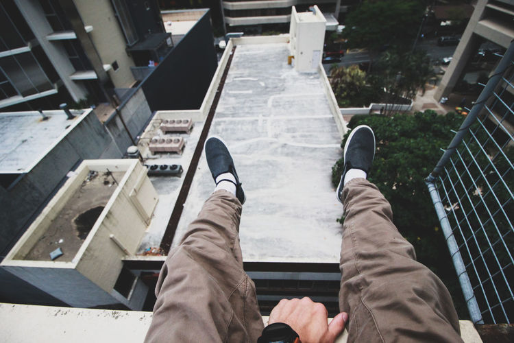 Low section of man sitting on retaining wall at building terrace