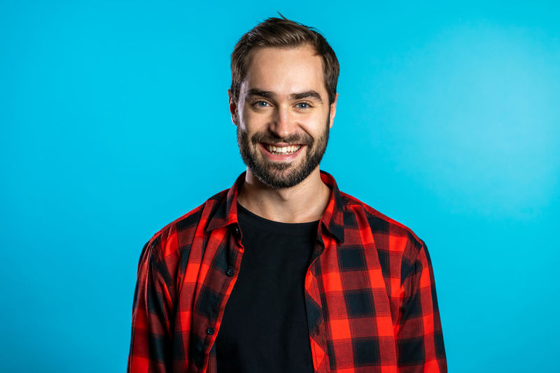 Portrait of smiling young man against blue background