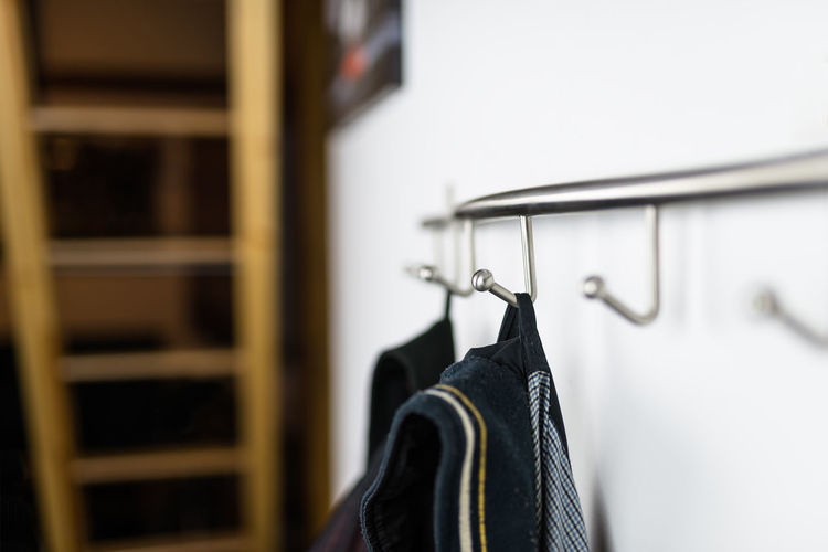 Close-up of clothes hanging on hooks on wall at home