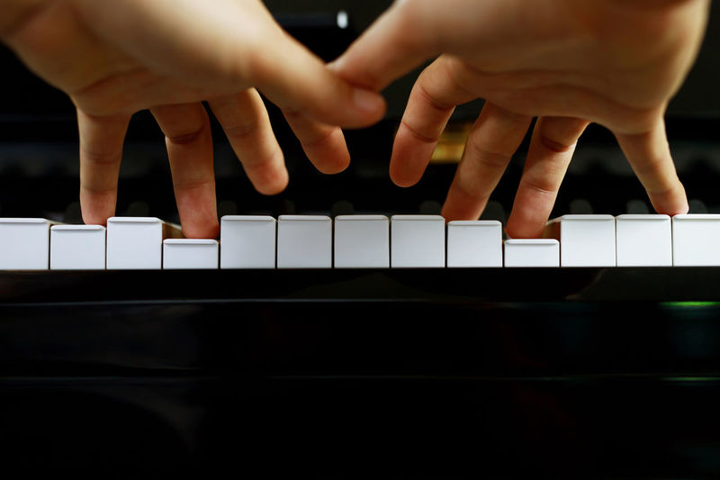 Cropped hands of woman playing piano