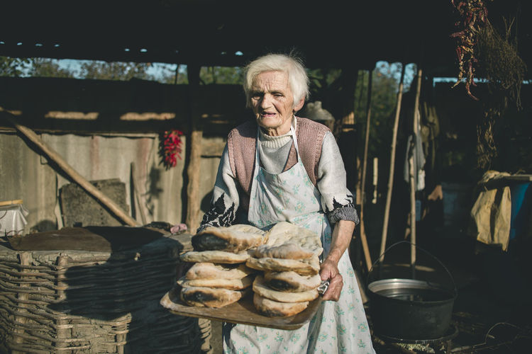 Portrait of smiling young woman holding food outdoors