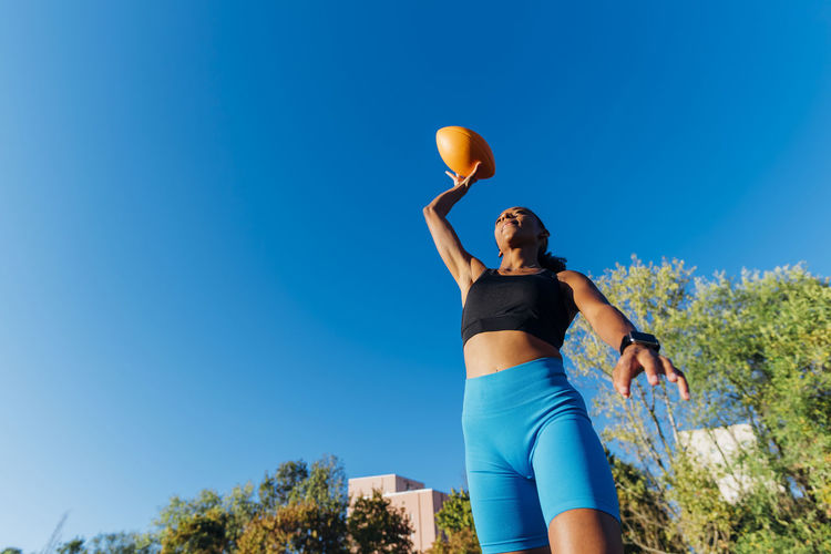 Young sports player throwing american ball on sunny day