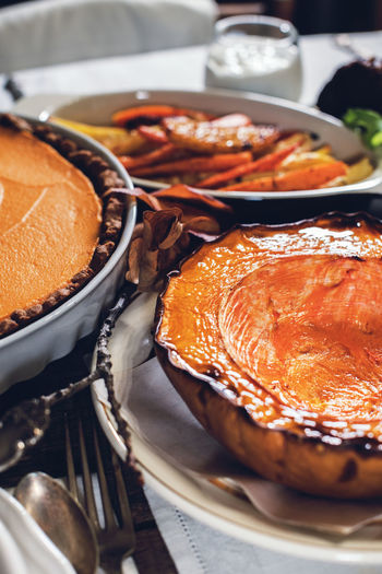 Pie and baked pumpkin setting table on thanksgiving day celebration dinner on rustic table