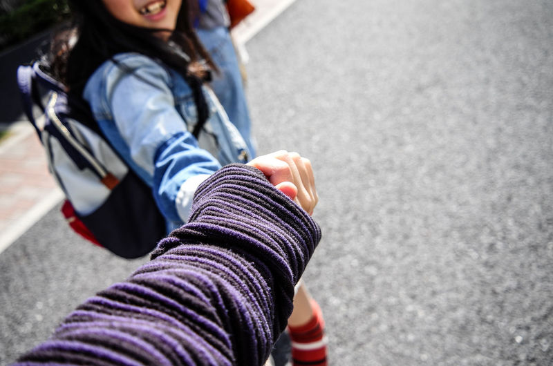 Close-up high angle view of friends holding hands on street