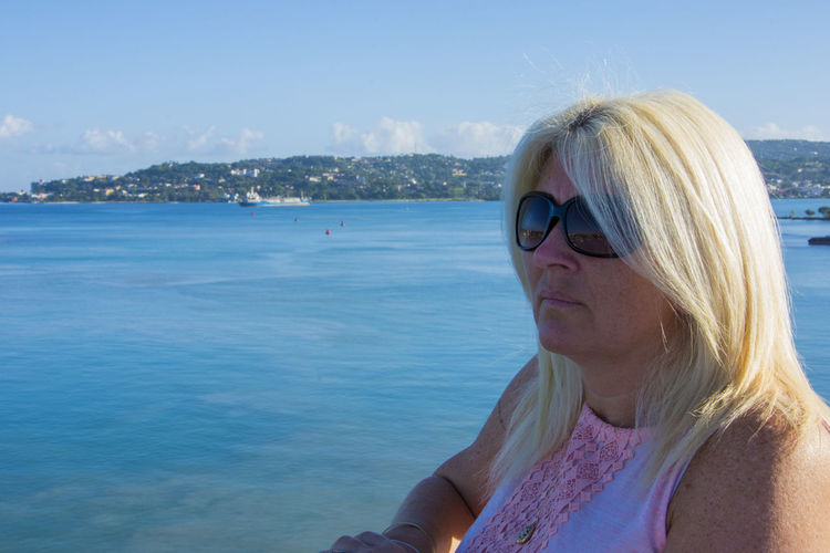 Mid adult woman wearing sunglasses standing against sea