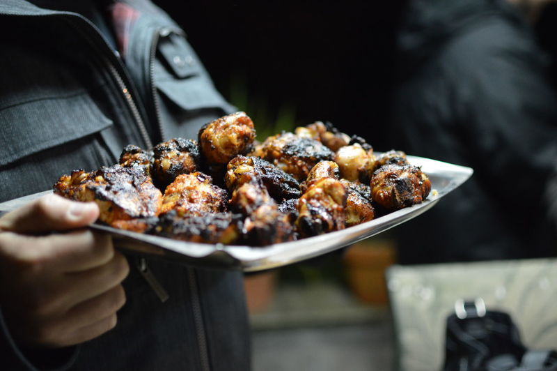 Close-up of hand holding grilled meat in plate