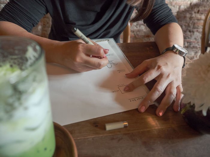 High angle view of woman hand holding paper at table