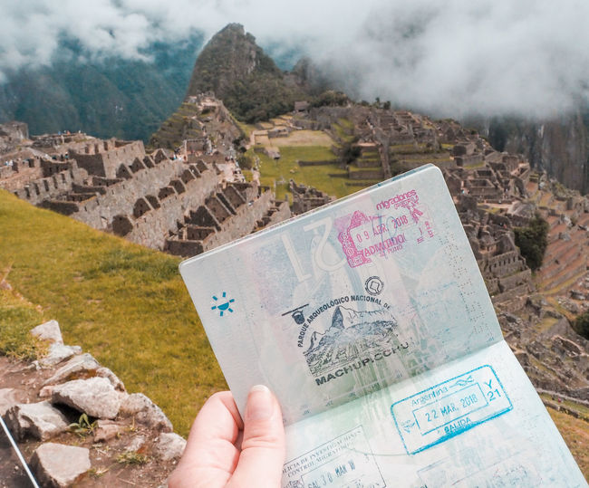 Cropped hand holding passport against machu picchu