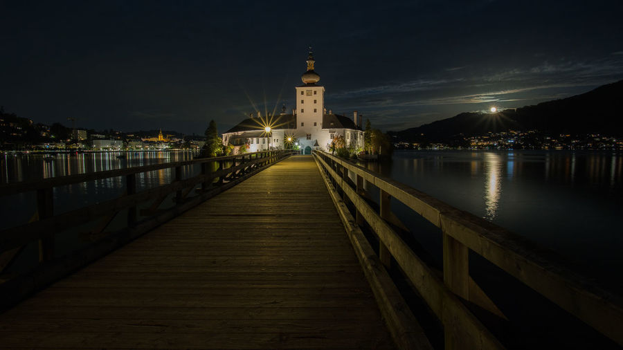 Pier over river against sky at night