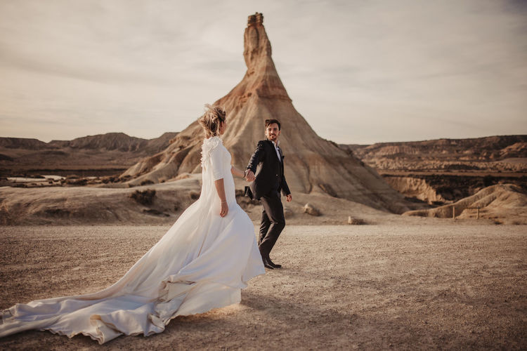 WOMAN WITH UMBRELLA STANDING ON DESERT LAND