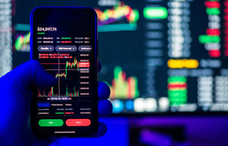 Stock and crypto trading online platforms displayed on a smartphone and desktop screens.