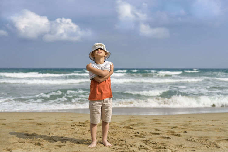 Full length of boy standing at beach against sky
