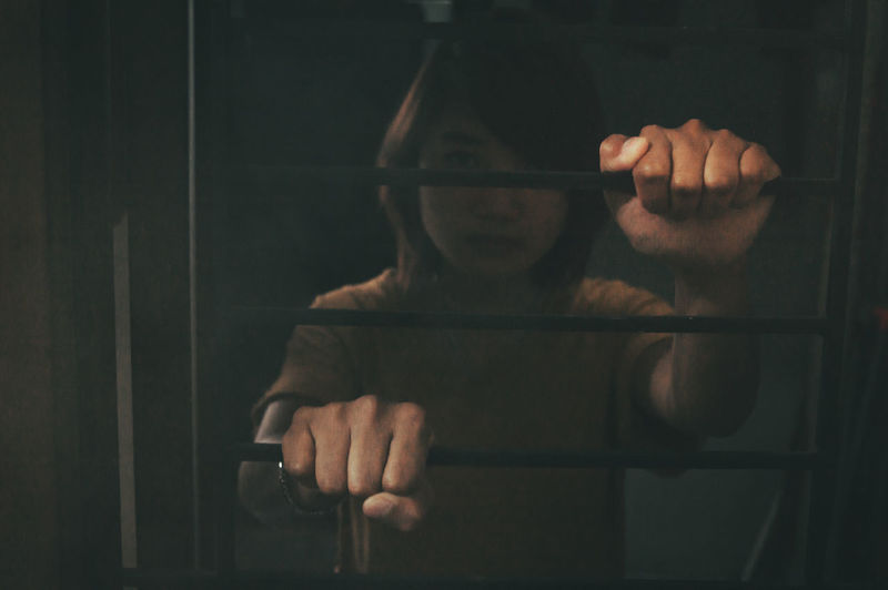 Portrait of woman holding window in darkroom