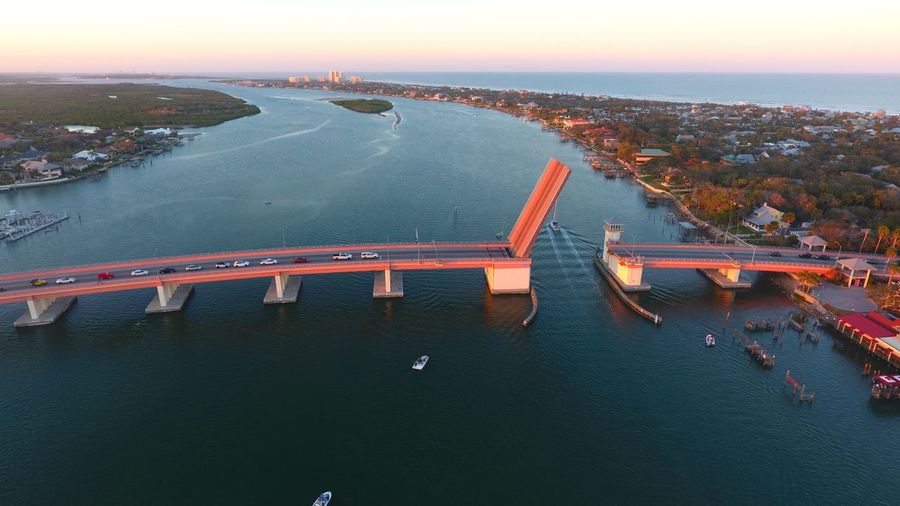 High angle view of illuminated bridge over river in city at sunset