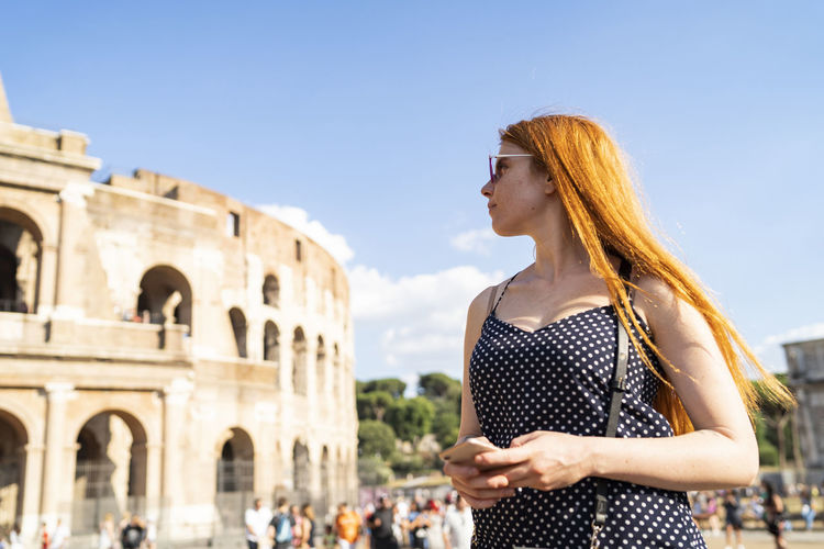 Young woman with smartphone admiring famous attraction