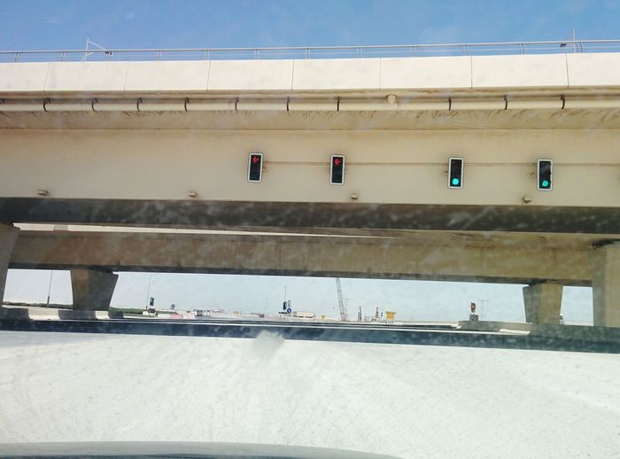 Stoplights on bridge over road seen through windshield