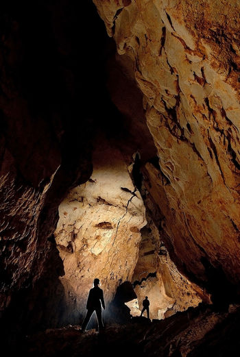 Silhouette people standing in cave