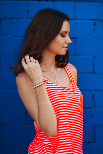Woman in red tank top standing against brick wall