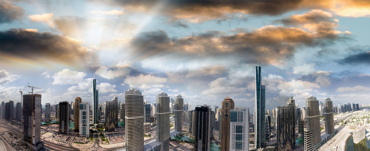 Panoramic view of city buildings against cloudy sky