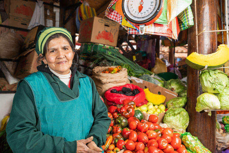 Peruvian female seller standing near stall with fresh tomatoes on itinerant fair