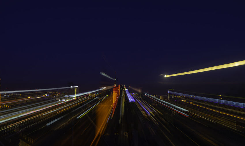 Light trails on highway in city against clear sky at night