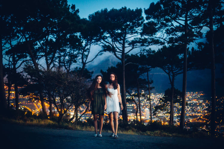 Young women against trees at night