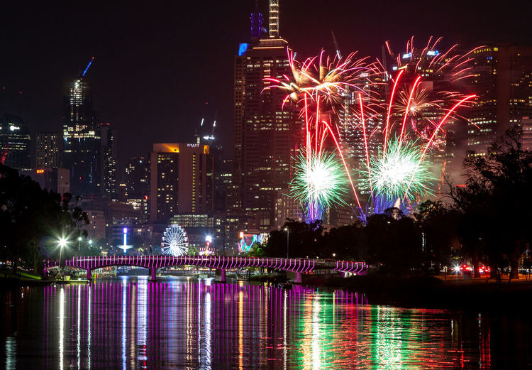 Firework display over river and buildings at night