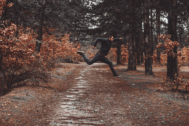 Man jumping in forest during autumn